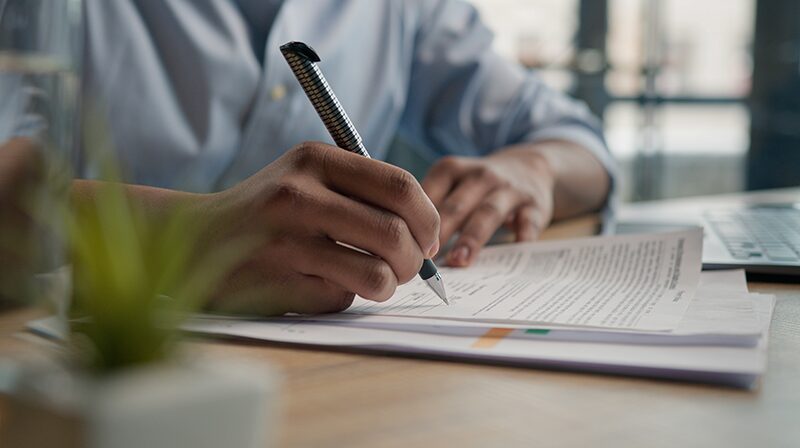 A close view of hands completing paperwork with a pen.